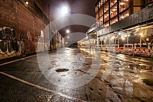 Asphalt street road in night city after the rain. Parking lot with graffiti on the brick walls