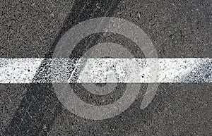 Asphalt texture with white line and tire marks. Top view