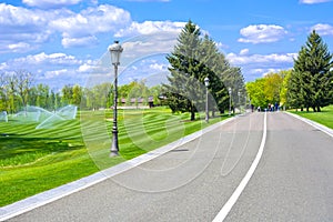 Asphalted road between golf courses with lanterns