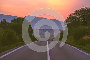 Asphalted road leading up to the mountains in forest - vintage r