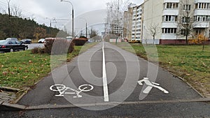 Asphalted sidewalks and a bike path are laid between the carriageway of the street with parked cars and residential buildings. Shr