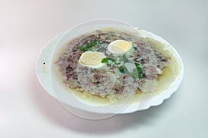 Aspic with meat, eggs and fresh parsley, made with thick and rich nutritious bone broth, frozen in elegant white porcelain plate