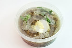 Aspic with meat, eggs and fresh parsley, made with thick and rich nutritious bone broth, frozen in round transparent plastic food