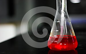 Aspirating a red chemical on a glass conical flask with a pipette in a chemistry lab photo