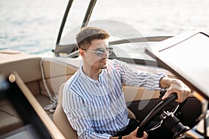 Aspirational successful businessman standing by luxury boats and yachts against a deep blue sky, holding his jacket over