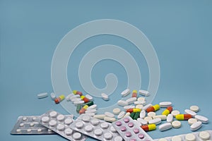 Aspirin and antibiotic pills, vitamins capsules on blue background. Copy space. The concept of health care, protection from the