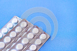 Aspirin in a blister on top. Vitamin C pills in a pack. White tablets in a blister on a blue background close-up with soft focus.