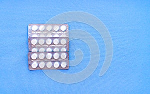 Aspirin in a blister on top. Vitamin C pills in a pack. White tablets in a blister on a blue background close-up with soft focus.