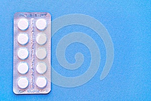 Aspirin in a blister on top. Vitamin C pills in a pack. White tablets in a blister on a blue background close-up with soft focus.