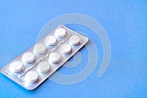 Aspirin in a blister on top. Vitamin C pills in a pack. White tablets in a blister on a blue background close-up with soft focus.