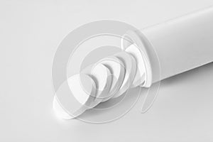 Aspirine tablets coming out from its tube  on white background with copy space for your text photo