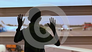 Aspiring Pilot: Boy Watches Airplanes at Airport Window