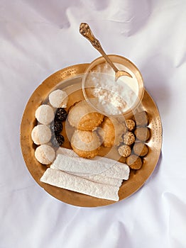 Assamese traditional food items like pitha, laddu, doi sira with assamese gamosa background