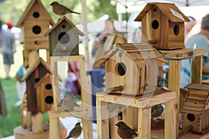 assembled birdhouses displayed on stands at a craft fair