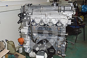 The assembled four-cylinder car engine is installed on the engine repair stand