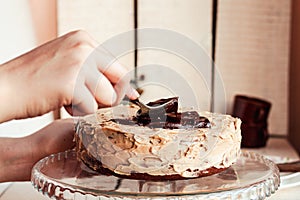 Assembling the chocolate cake. Woman hands spread chocolate cream frosting on top of cake layer. Step by step chocolate cake