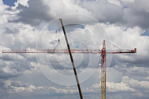 Assembling of crane on dramatic cloudy background. Dangerous height situation.