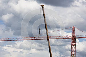 Assembling of crane on dramatic cloudy background. Dangerous height situation.
