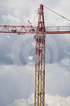 Assembling of crane on dramatic cloudy background. Dangerous height situation.