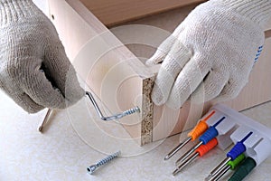 Assembling  furniture box, gloved hands tighten  screw with  key, close-up