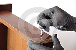 Assembling furniture, gloved hands tighten screw with key, close-up