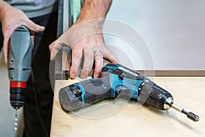 Assembling furniture with a power tool. A carpenter works in a workshop customizing details of a future product. Unrecognizable