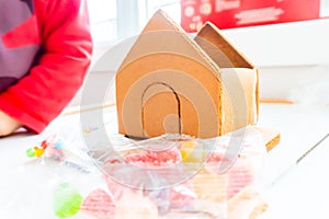 Assembling a gingerbread house at Christmas time, with icing sugar as the bonding `glue.` A classic holiday activity, making a