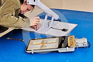 Assembling stand alone solar street light, an electrician attaches solar module and LED luminary to light arm or