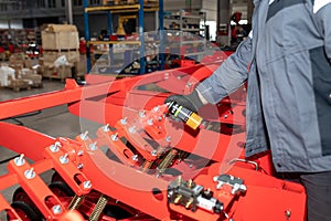 Assembly of agricultural machinery. Worker treats joints with spray can