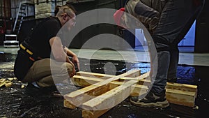 Assembly of wooden stage construction by young builders. Media. Men workers using logs for the decorations of the