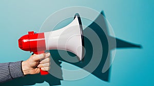Assertive communication hand holds megaphone casting sharp shadow