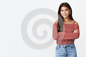 Assertive and confident good-looking young adolescent girl in striped blouse holding hands crossed on chest with ready