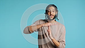 Assertive man asking for timeout, doing hand gestures, studio background