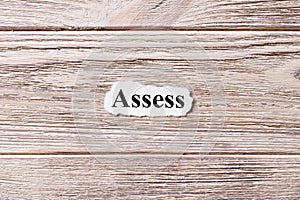 ASSESS of the word on paper. concept. Words of ASSESS on a wooden background