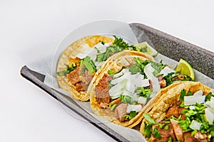 Asset three lengua cow tongue street tacos with cilantro and onion and lime wedges photo