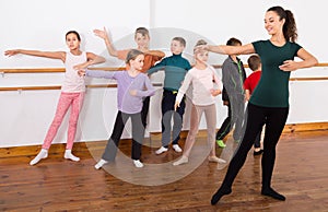 Assiduous boys and girls rehearsing ballet dance in studio