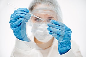 Assistant in blue gloves putting reagent onto slide making coronavirus test