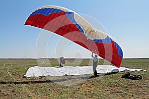 Assistant helps the paraglider to straighten the paraplane before the flight in Volgograd