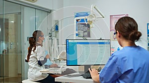 Assistant making appointments while dentistry doctor is examining man