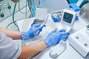 Assistant`s hands configures dental equipment in dentist`s office. Close up, selective focus. Dentistry photo