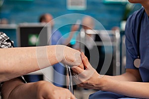 Assistant support worker holding disabled senior female patient hands