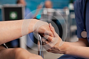 Assistant support worker holding disabled senior female patient hands