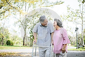Assisting her senior patient who`s using a walker