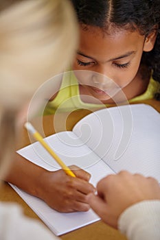 Assisting her students. A teacher explaining something to a student in her classroom.