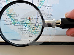 Handheld magnifying glass over atlas page of Greenland photo