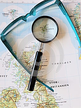 Magnifying glass and eyeglasses on danish atlas page over atlas page photo