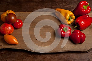 Assort of different shape and color tomatoes and bell pepper on wooden background