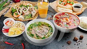 Pho bo, pho tom, noodles, spring rolls, tom yam, rice, mango shake on beautiful black stone table