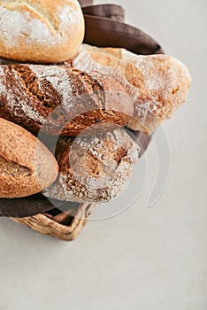 Assorted bakery products including loafs of bread, baguette and rolls in basket