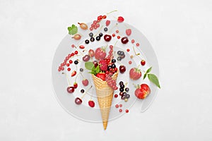 Assorted berries in waffle cone on light background from above. Dietary and healthy dessert. Flat lay styling.